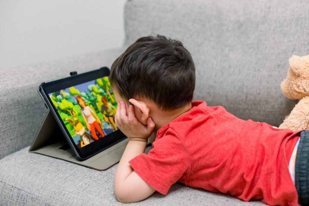 Little boy laying on a couch watching shows on YouTube